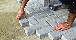 a man laying block paving for a driveway