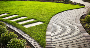 a landscaped garden with a winding brick path through a grass lawn