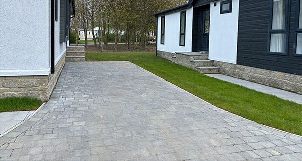 a block paved driveway leading up to two bungalows