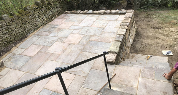 a raised brick patio being laid in a back garden