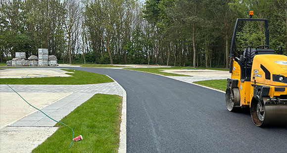 a newly laid tarmac road with a drum roller parked on it