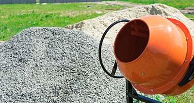 an orange cement mixer next to some cement used as an ingredient for concrete